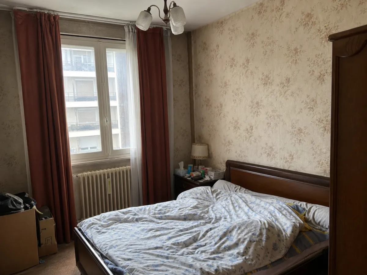 Chambre très personnelle avant home staging : papier peint fleuri, lit défait, chevet encombré